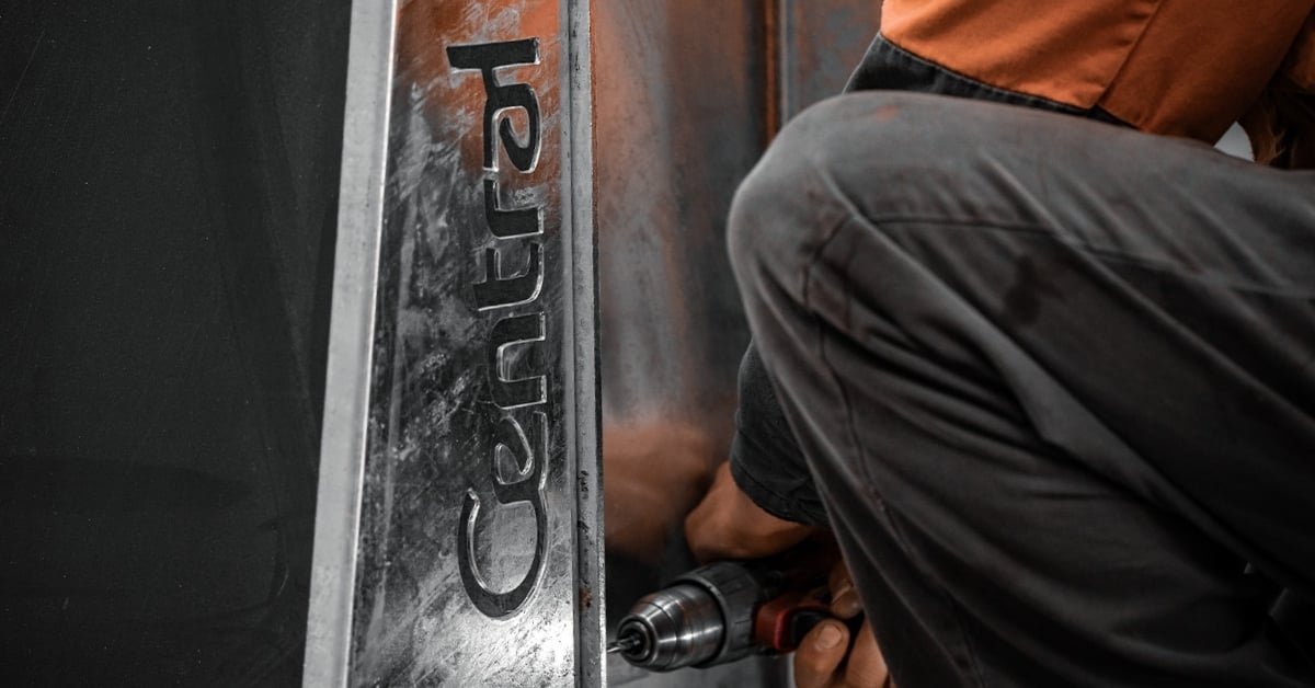 A steel worker joining two hot dip galvanised steel sections, one imprinted with the Central Steel Build logo.