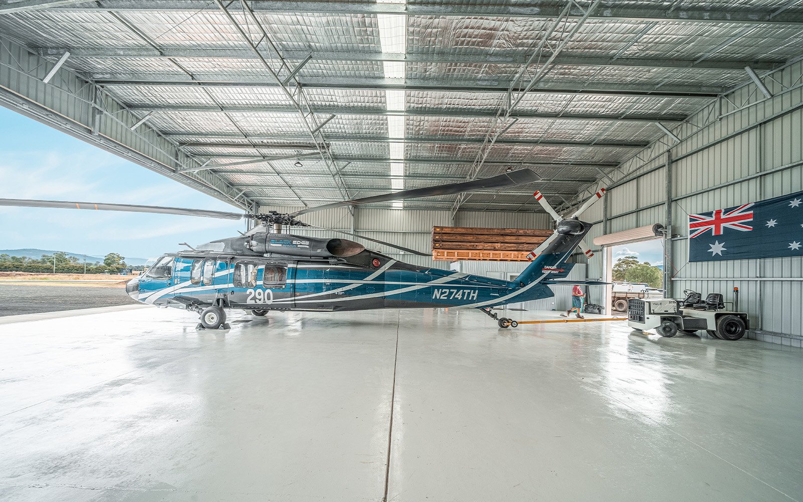 The interior of a helicopter hangar in the Hunter Valley NSW, with a parked Black Hawk and a airstrip vehicle in view.