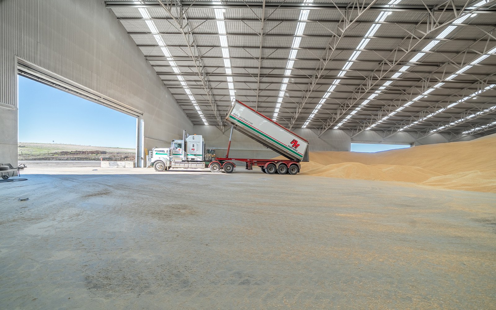 Interior of the Porthaul grain storage shed in Portland, Victoria, showing a truck unloading grain inside a large-scale agricultural steel building designed and constructed by Central Steel Build.
