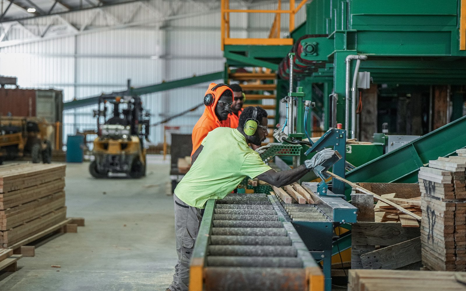 Workers managing sawmill machinery inside Morgan Sawmill’s large industrial steel shed, showcasing durable structure and efficient manufacturing design.